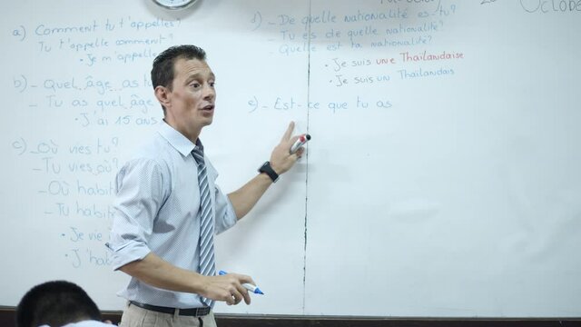 A French teacher, and also a French native, is teaching high school students about basic Q&A for introductions.