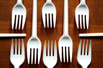 Some plastic forks placed in a geometric pattern, on a wooden table.