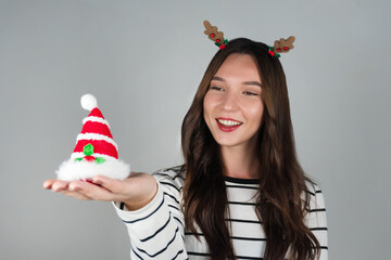 A happy woman holds a Christmas decoration. Grey background