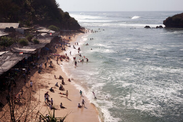 Views of beaches in the morning on holiday seasons with people and tourists swimming and sunbathing captured high angle.