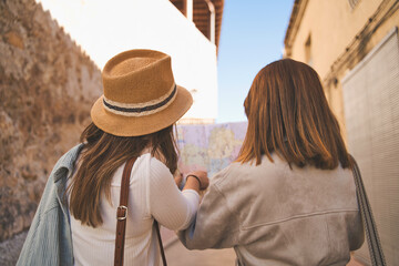 Back view journey of two young women looking at the map.