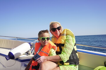 Boat ride on the sea along the rocky shore. Mother and son on a boat trip. Turquoise water and blue...