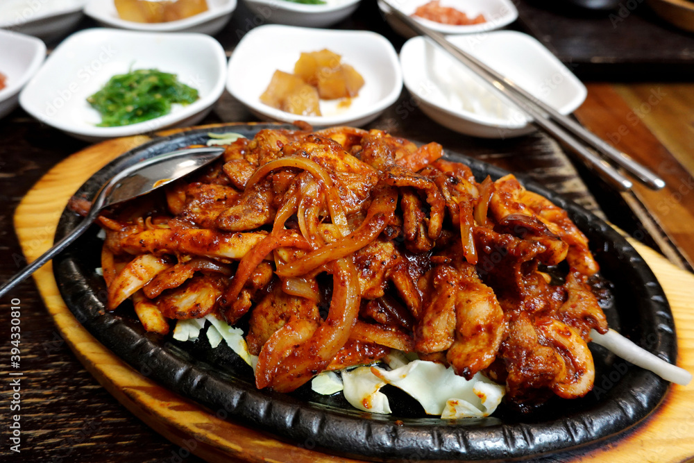 Wall mural Korean Sizzling pork and squid with side dishes on wooden table