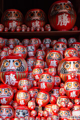 Daruma, round traditional Japanese dolls decorated in the garden of Katsuou-ji temple in Minoh, Osaka, Japan.  Notes: Japanese character on daruma means "happiness" or "Win".
