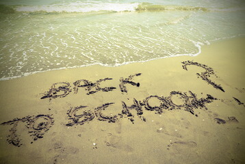 text BACK TO SCHOOL written in the sand of the beach with questi