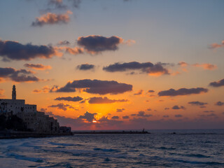 Fototapeta na wymiar Coastal view of the ancient city of Yafo or Jaffanear Tel Aviv, Israel. Cityscape in sunset hour with clouds in the sky.
