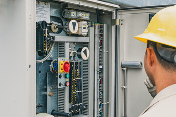 An electrician is inspecting the equipment in the field of the power sub-station.
