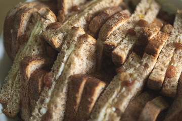 Close up of from above of slices of brown bread with butter, jam and raisins, ready to become a bread pudding once the custard is poured. Home made desserts, traditional recipe, hearty cooking.