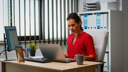 Woman using laptop and pc in same time in office room. Entrepreneur working in modern professional workspace, workplace in personal corporate company typing on computer keyboard looking at desktop