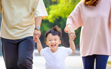 happy little boy walking with parent in the park