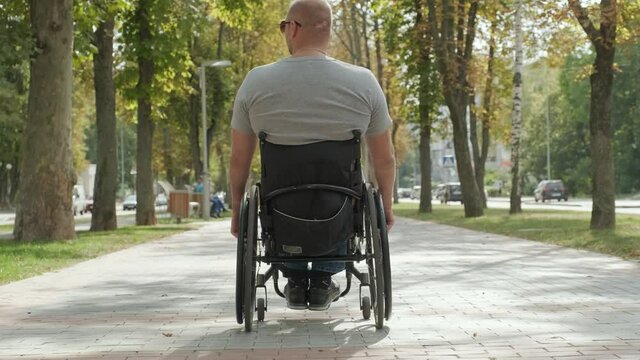 Handicapped man in wheelchair walk at the park alley