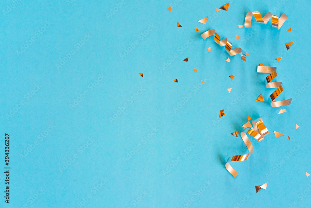 Wall mural close up on group of gold color of rolling ribbon and confetti on teal background with copy space fo