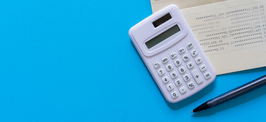 close up top view on calculator with bank account passbook and pencil on blue color background for...