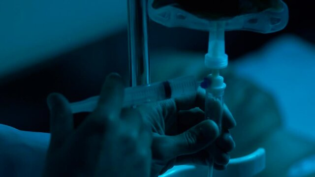 A male doctor injects medicine into an IV by opening a valve. Caring for the sick. Medical or science laboratory concept.