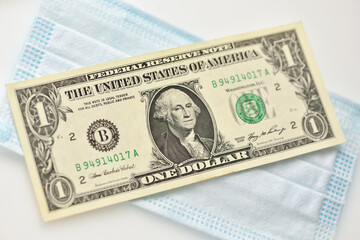 One dollar bill lies on a medical mask on a white background