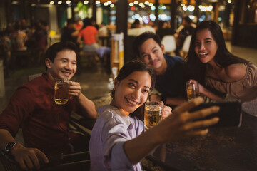 Asian friends Drinking beer outdoors at the brewery for the New Year festival.She is taking a selfie