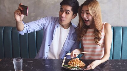 Young asian  man and woman  eating at restaurant . Couple travel and taste noodles and street food .