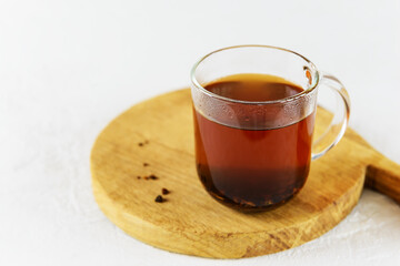 Chaga tea in a glass mug on a wooden board.