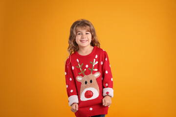 Cute little girl in red Christmas sweater smiling against orange background