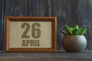 april 26th. Day 26 of month, date in frame next to succulent on wooden background spring month, day of the year concept