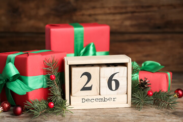 Block calendar with Boxing Day date near gifts on wooden table