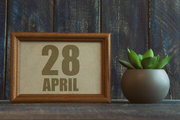 april 28th. Day 28 of month, date in frame next to succulent on wooden background spring month, day...