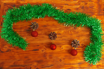 Pine cones and Christmas balls decorated with shiny tinsel on a wooden table top close up