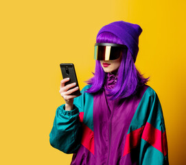 Style woman in VR glasses and 80s tracksuit with mobil ephone on yellow background