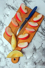 Knife, Apple and melon slices on a chopping Board close-up