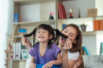 Mother having fun and playing with her daughter at home, family concept