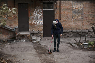 Obraz na płótnie Canvas A guy in a gas mask walks a toy dog during quarantine covid 19