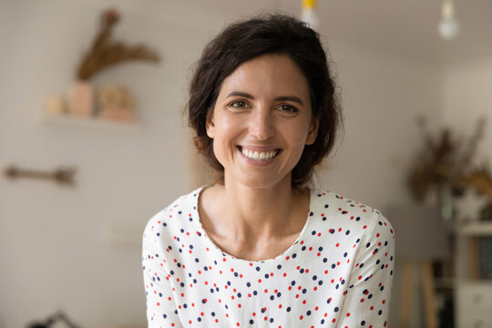 Close Up Headshot Portrait Of Smiling Young Caucasian Woman Look At Camera Pose In Flat Apartment. Profile Picture Of Happy Millennial Female Renter Or Tenant Feel Satisfied Excited Show Optimism.