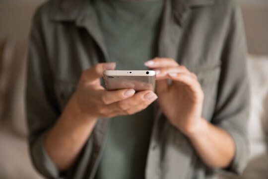 Crop close up of woman text message on modern cellphone gadget at home. Female client customer look at screen browse surf wireless internet connection on smartphone device. Technology concept.