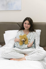 Teenage girl in pyjamas with a Teddy bear on Sunday morning