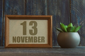 november 13th. Day 13 of month, date in frame next to succulent on wooden background autumn month, day of the year concept