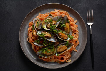 Pasta in tomato sauce with fried mussels, and herbs