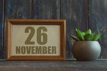 november 26th. Day 26 of month, date in frame next to succulent on wooden background autumn month, day of the year concept