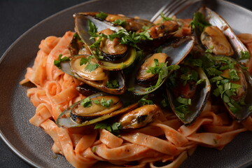Pasta in tomato sauce with fried mussels, and herbs