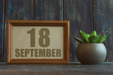 september 18th. Day 18 of month, date in frame next to succulent on wooden background autumn month, day of the year concept