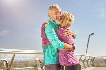 Fototapeta na wymiar Support. Happy mature family couple in sportswear smiling while hugging after having workout in the city park on a sunny morning. Joyful senior couple working out together outdoors