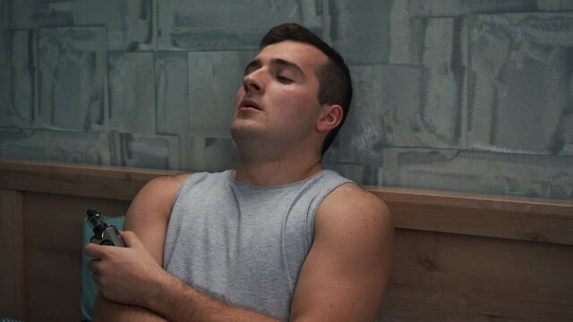 a man smokes a vape lying on the bed