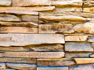 the texture of the wall is made of uneven stones of different sizes of sand and light brown color.. stone background