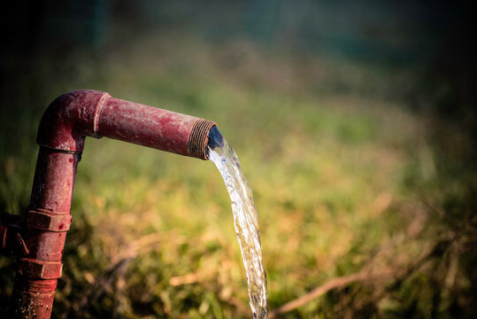 Water wastage. Fresh water flowing out from a steel pipe.