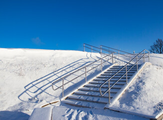 Winter staircase covered with snow on a cold clear and sunny weather under the blue sky