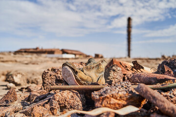 old worn down shoe with an abandoned saltpeter mining town in the blurry background the Atacama desert of Chile, South America