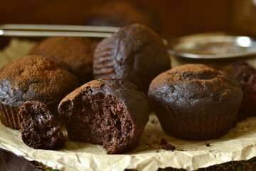 Chocolate banana muffin sprinkled with cocoa on dark background