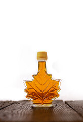 Maple syrup in glass bottle on wooden table on white background