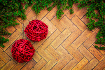 Christmas or New Year decoration background with hanging red baubles in pine branches on a wooden table with copy space.