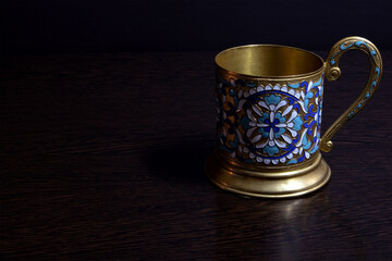 Old fashioned glass holder of brass with color enamel pattern, vintage utensil of russian soviet period 