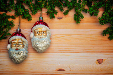 Christmas or New Year decoration background with hanging two Santa Clauses in pine branches on a wooden table with copy space.